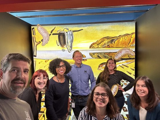 A group of people taking a photo in front of a large contemporary artwork. 